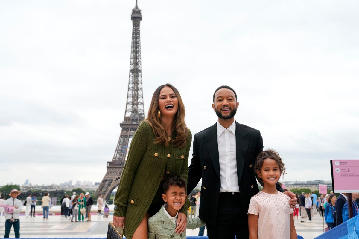 Chrissy Teigen and John Legend standing with children Miles and Luna with the Eiffel Tower in the background