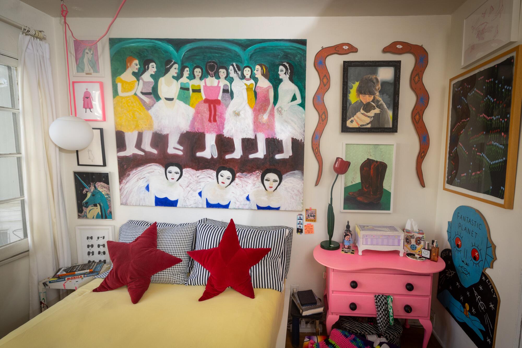 Red star and black and white pillows decorate the bed in the bedroom, below a painting of dancers.