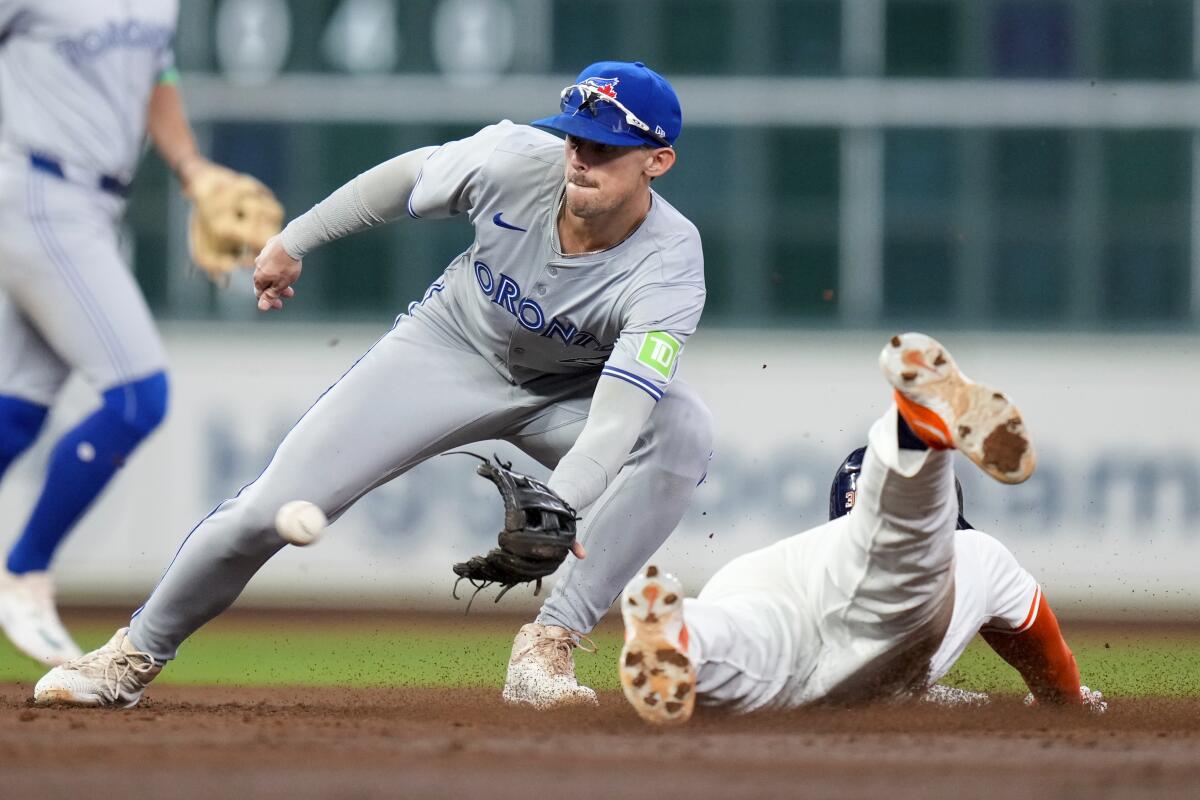 The Astros' Kyle Tucker, right, steals second as Blue Jays second baseman Cavan Biggio catches the throw.
