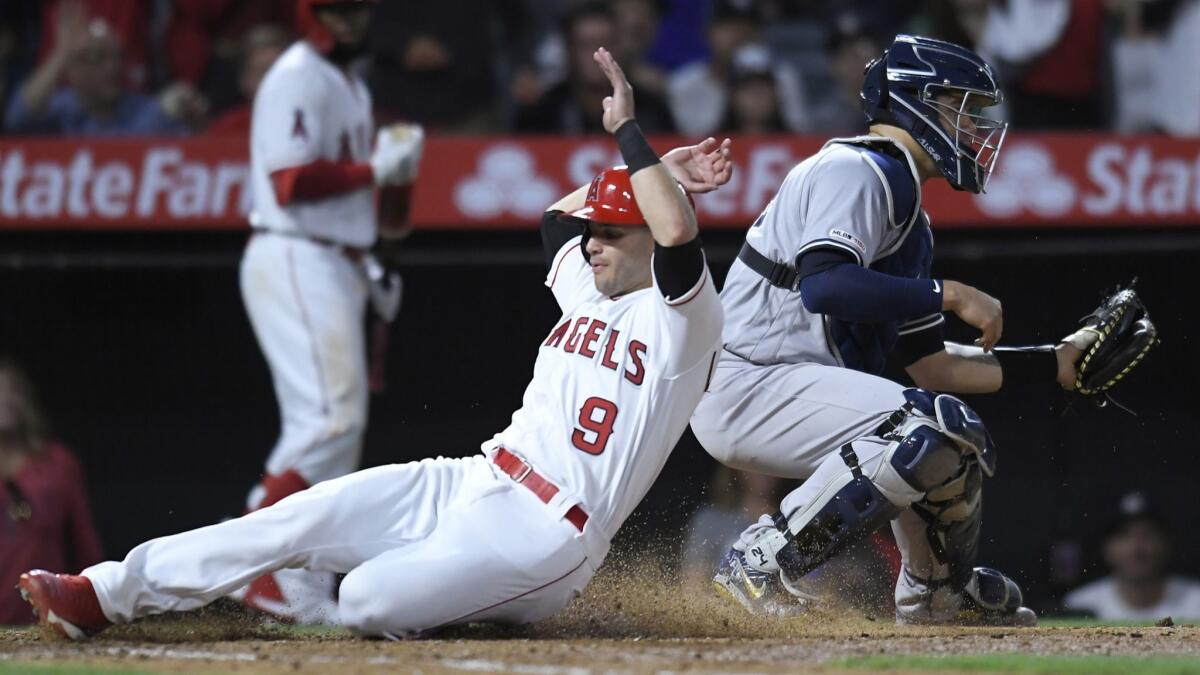 Tommy La Stella (9) of the Angels slides past Gary Sanchez (24) of the New York Yankees to score in the sixth inning at Angel Stadium.