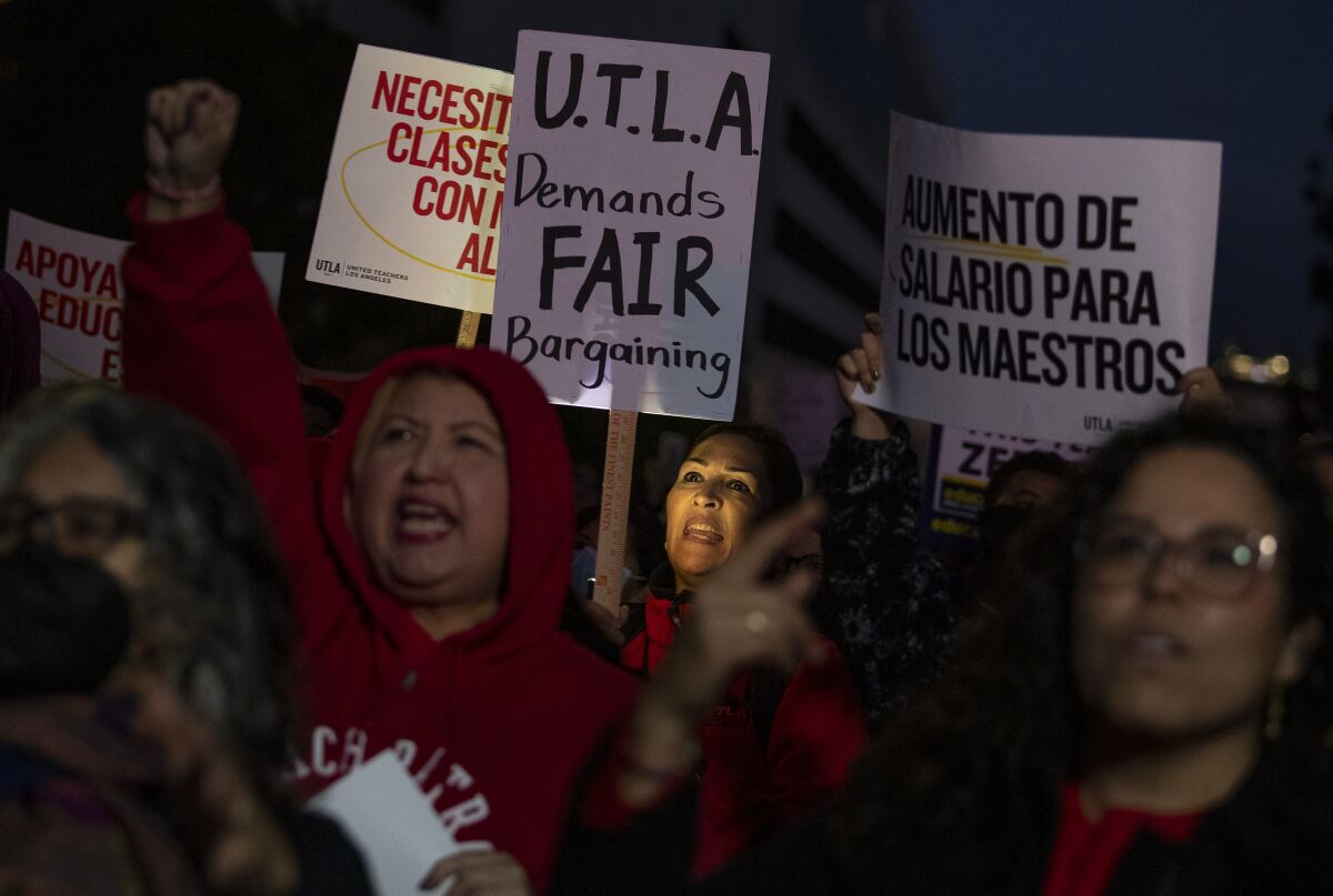 A crowd of people holding signs and chanting at night