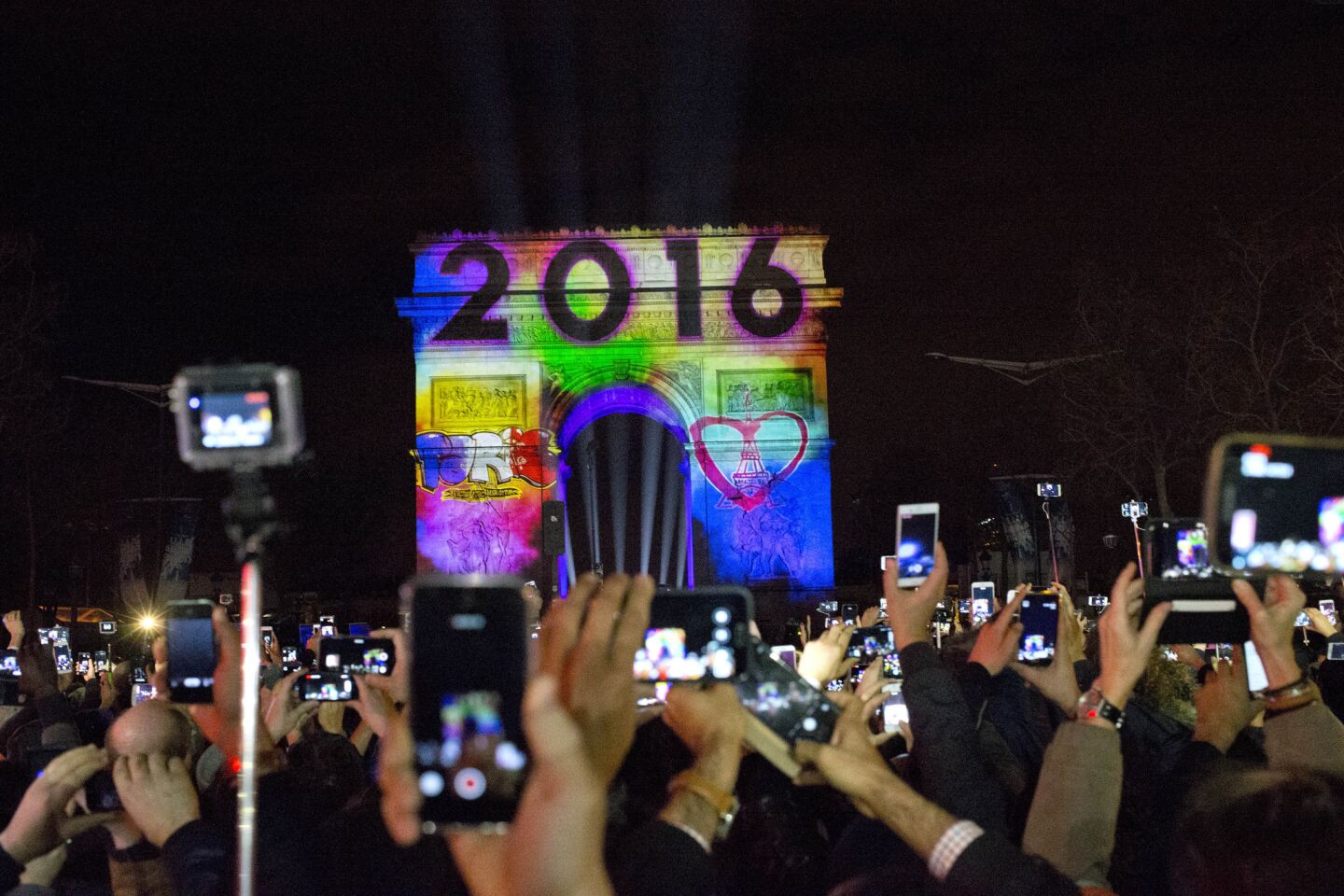 Revelers photograph a 5-minute video performance displayed on the Arc de Triomphe as part of New Year's Eve celebrations on the Champs-Elysees in Paris.