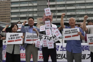 Demonstrators in Seoul, one wearing a Trump mask, hold signs.