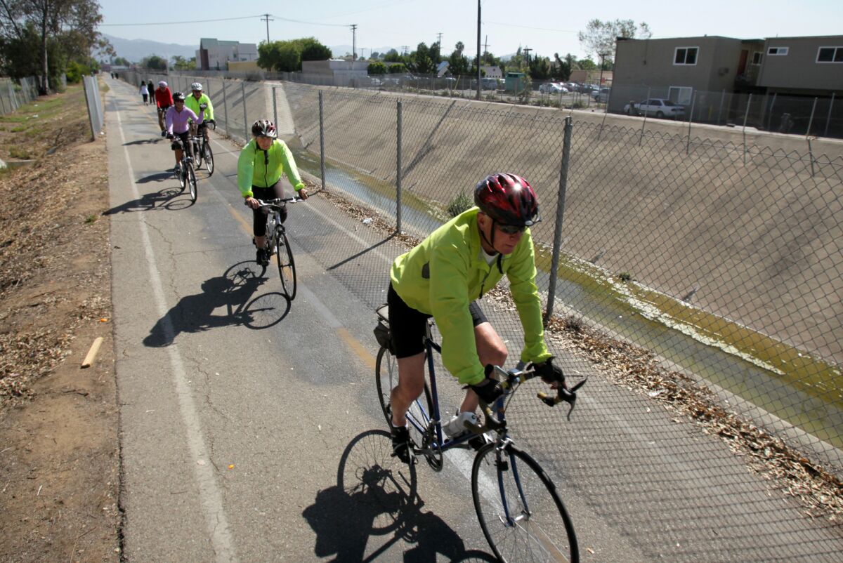 In this 2012 photo, bicyclists ride by a channelized section of Escondido Creek. 