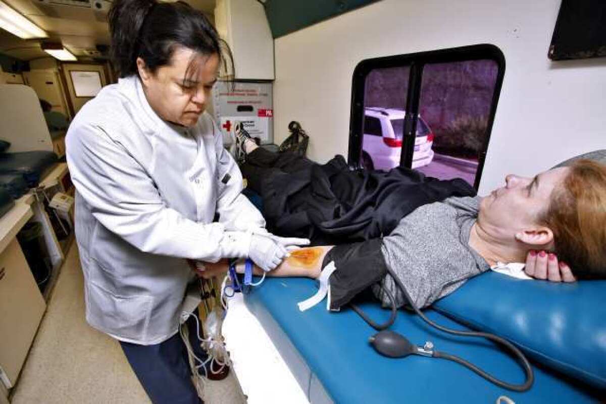 Blood donor Brenda Gant of La Crescenta is helped by American Red Cross Tech Norma Svanoe during the annual county-wide L.A. County Sheriff's "Battle of the Badges" at the La Crescenta Valley Station.
