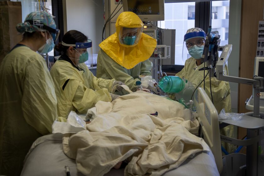 LOMA LINDA, CA - DECEMBER 15, 2020: Pulmonologist Dr. Laren Tan, center, with his medical team of nurses and respiratory therapists intubate a COVID-19 patient who's oxygen levels were dropping in the ICU at Loma Linda University Medical Center on December 15, 2020 in Loma Linda, California. The hospital is experiencing a huge surge in COVID-19 patients. Dr. Michael Matus, chief of hospitalist said they are currently admitting more than 15 patients a day. The hospital has added 5 additional Covid units in addition to ICU. Many of the ICU patients have underlying health issues. Once those patients get Covid, "It's a marathon that they can't run, said Dr. Tan.(Gina Ferazzi / Los Angeles Times)