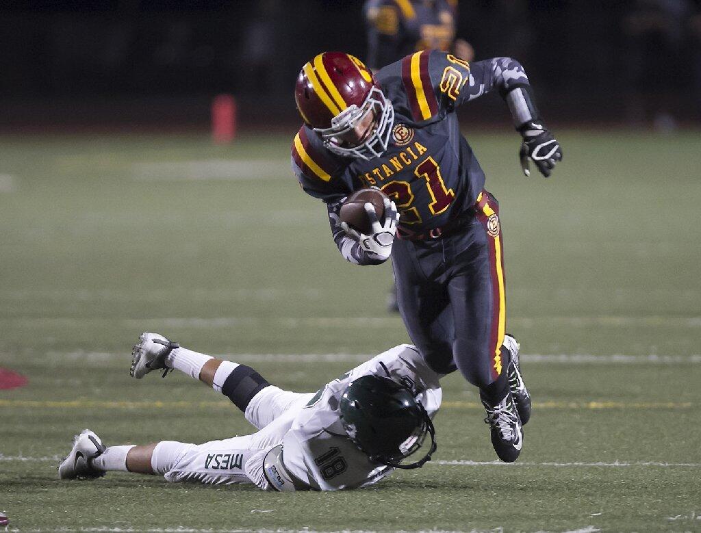 Estancia High's Jordan Alcazar (21) skips past a Costa Mesa tackler during the Battle for the Bell.