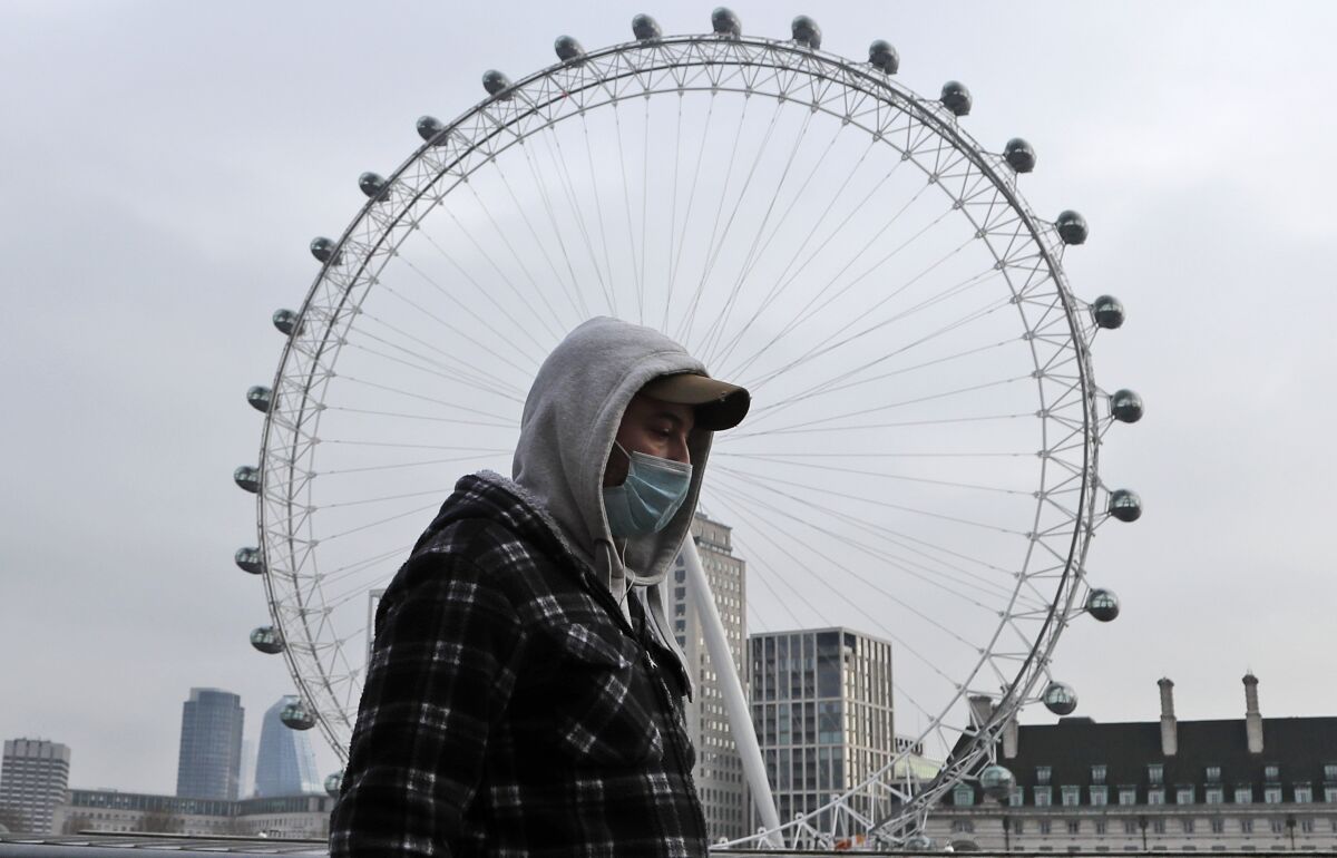 A man wearing a mask walks past the London Eye on Friday.