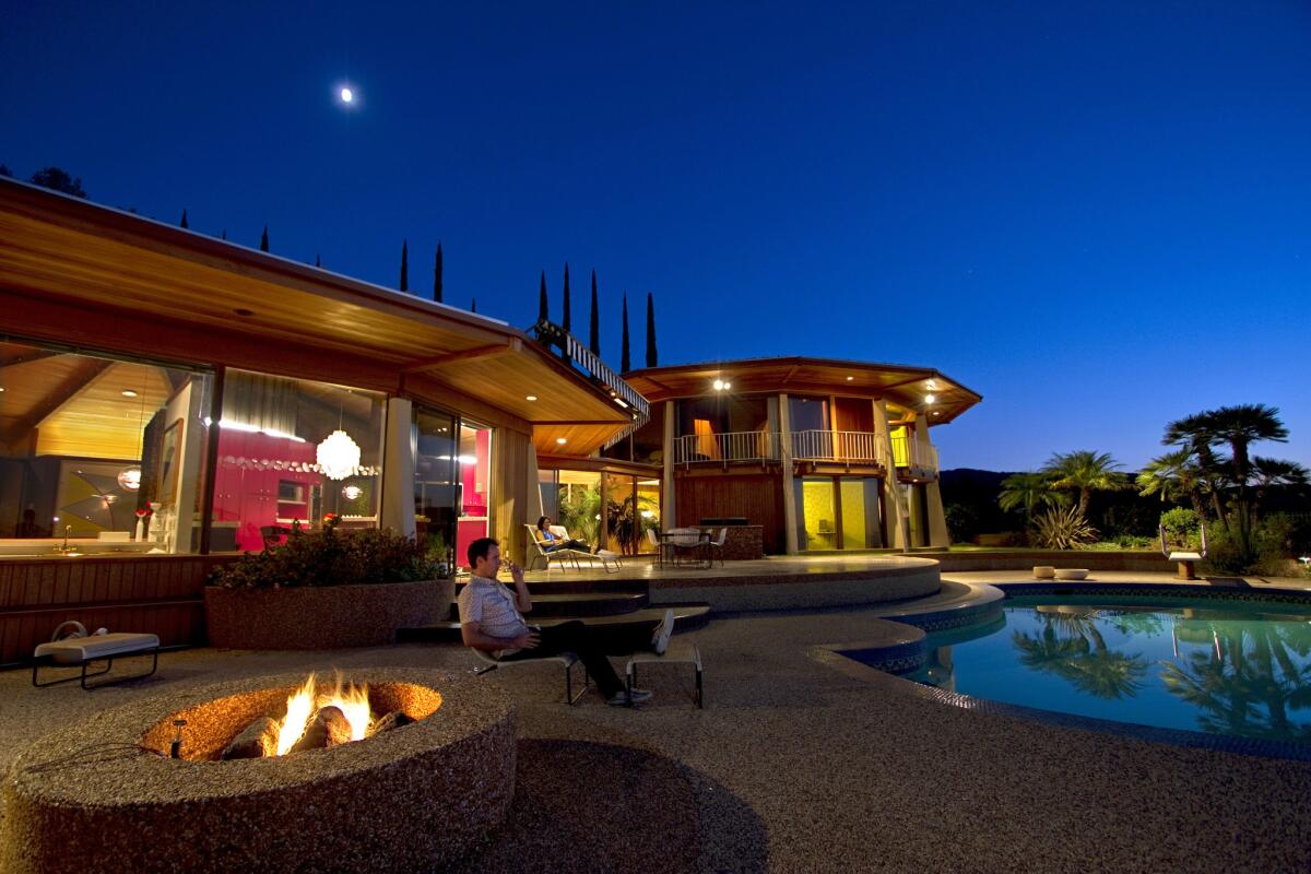 With the fire pit roaring and a Verner Panton chandelier lighting up a pink-purple kitchen with full-on 1970s style, the Loughreys' Encino house glows at twilight.