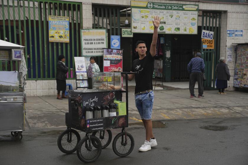 El venezolano Jhonier Marín saluda a un clientes antes de venderle café en Lima, Perú, el viernes 23 de agosto de 2024. (AP Foto/Guadalupe Pardo)