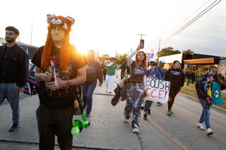 Demonstrators hold signs while marching in a street