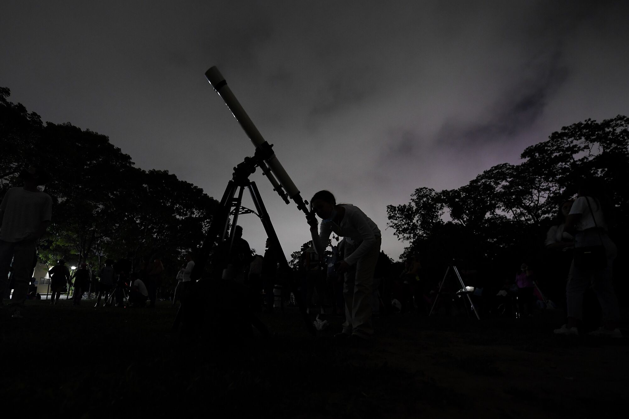 A person looks through a telescope at night