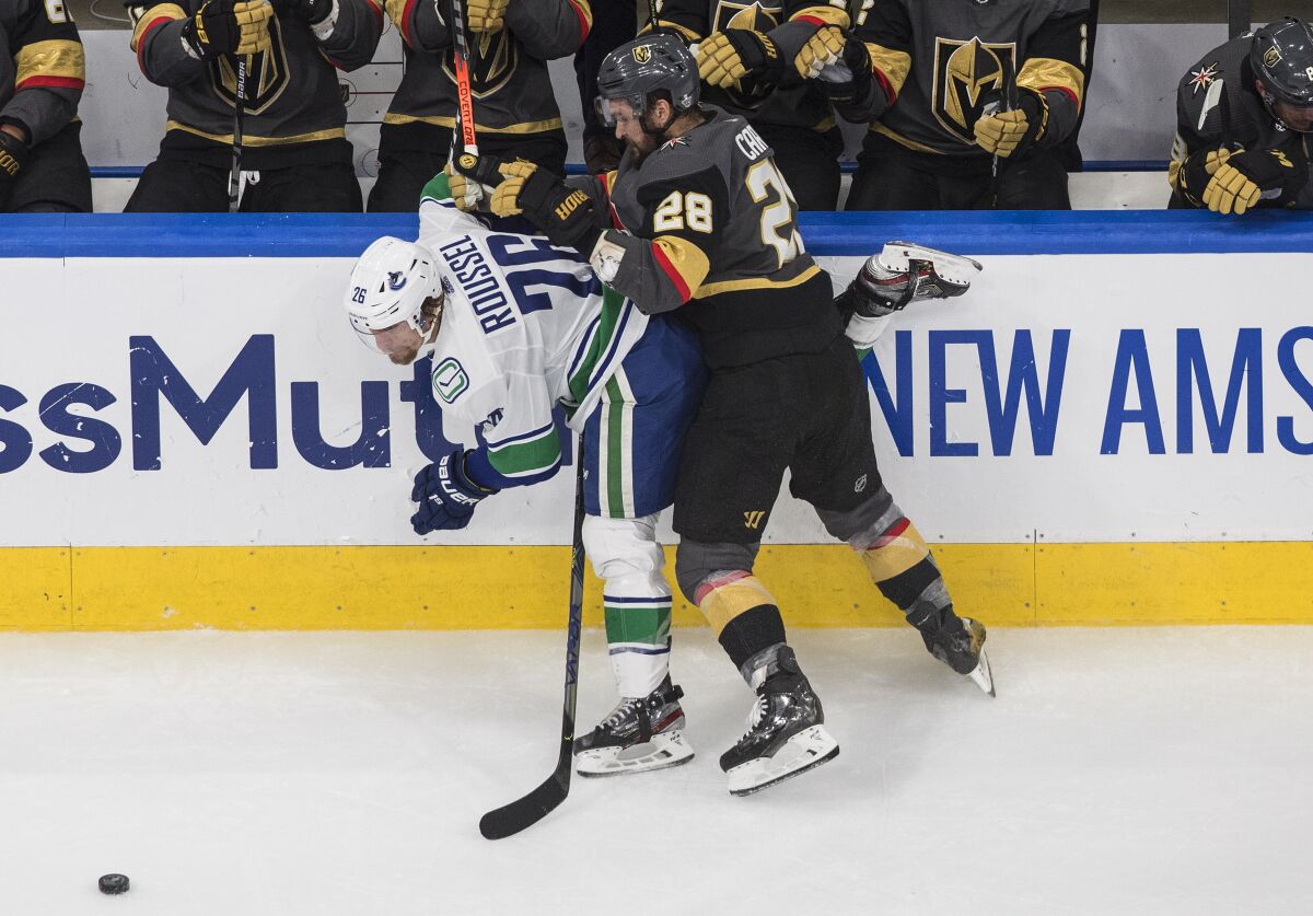 Vancouver Canucks' Antoine Roussel (26) is checked by Vegas Golden Knights' William Carrier (28) during second-period NHL Western Conference Stanley Cup playoff hockey action in Edmonton, Alberta, Friday, Sept. 4, 2020. (Jason Franson/The Canadian Press via AP)