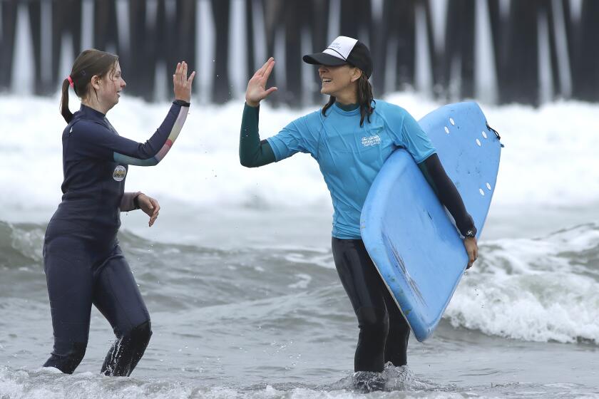 Oceanside, CA_ 6_4_24_|Hannah Wirth, 13, left, who attends TERI's Country School and Learning Academy, gives a hearty high-five to her volunteer surf instructor Sierra Brasher as they emerge from the waves south of Oceanside Pier Tuesday morning.| Surfin' Fire surf school in Oceanside, had volunteer surf instructors out just south of Oceanside Pier helping students from TERI's Country School and Learning Academy as they learned to surf most of them, for the first time. Photo by John Gastaldo for the Union-Tribune