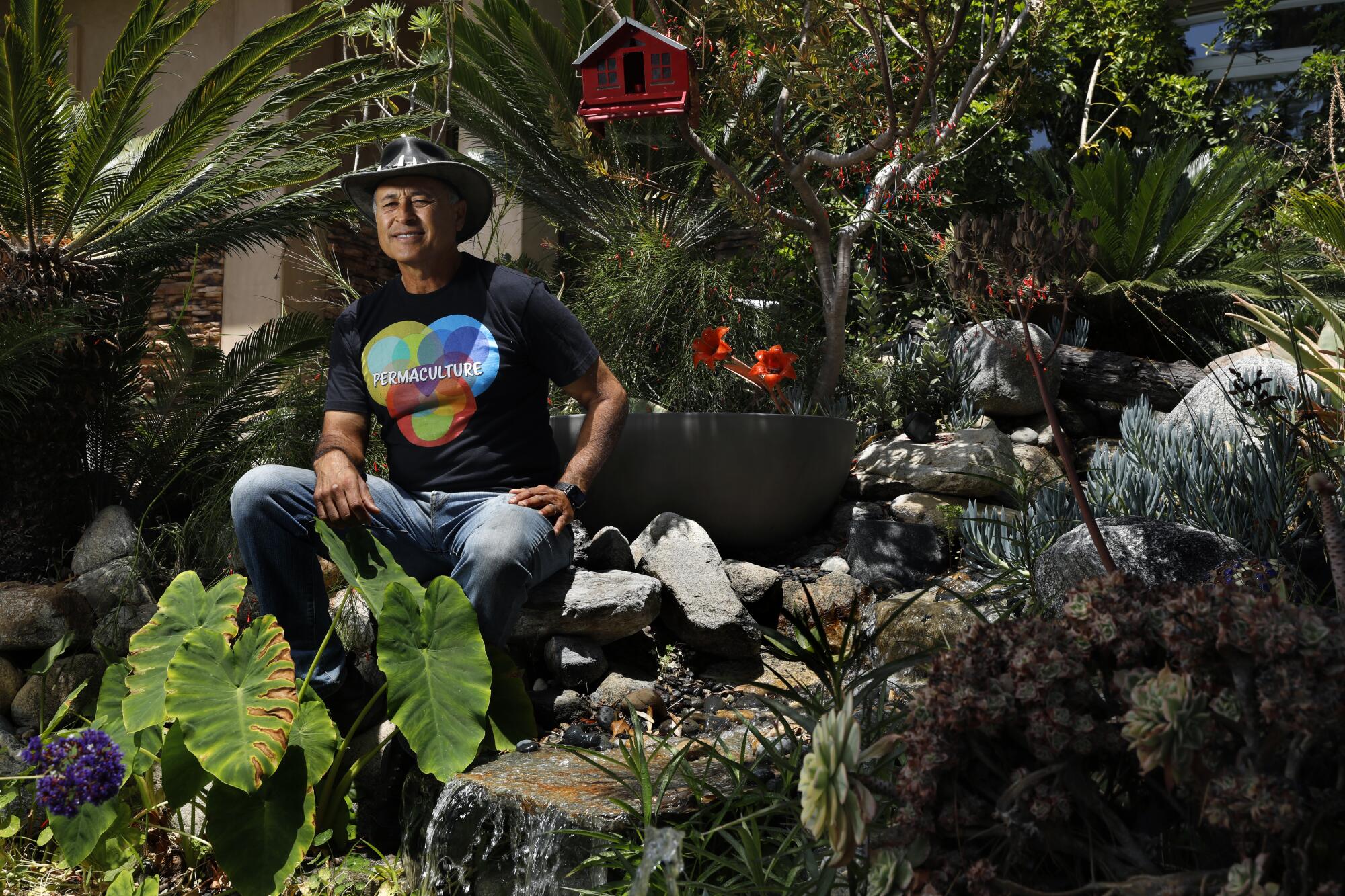 Mike Garcia sits surrounded by plants in his front yard.