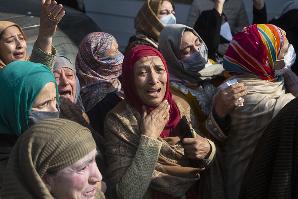 A group of women in headscarves gesture and cry.