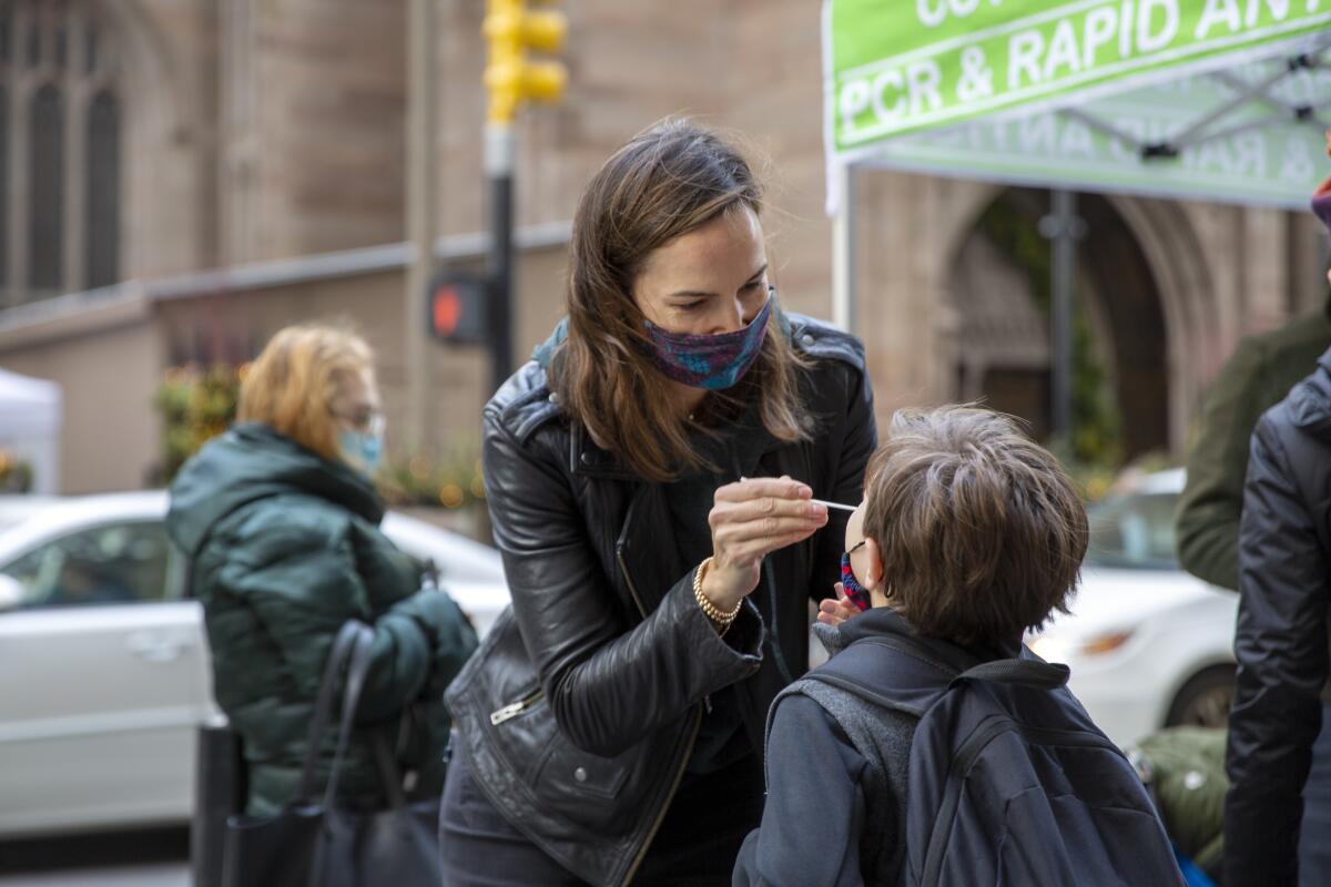 A mother swabs her son's nose.