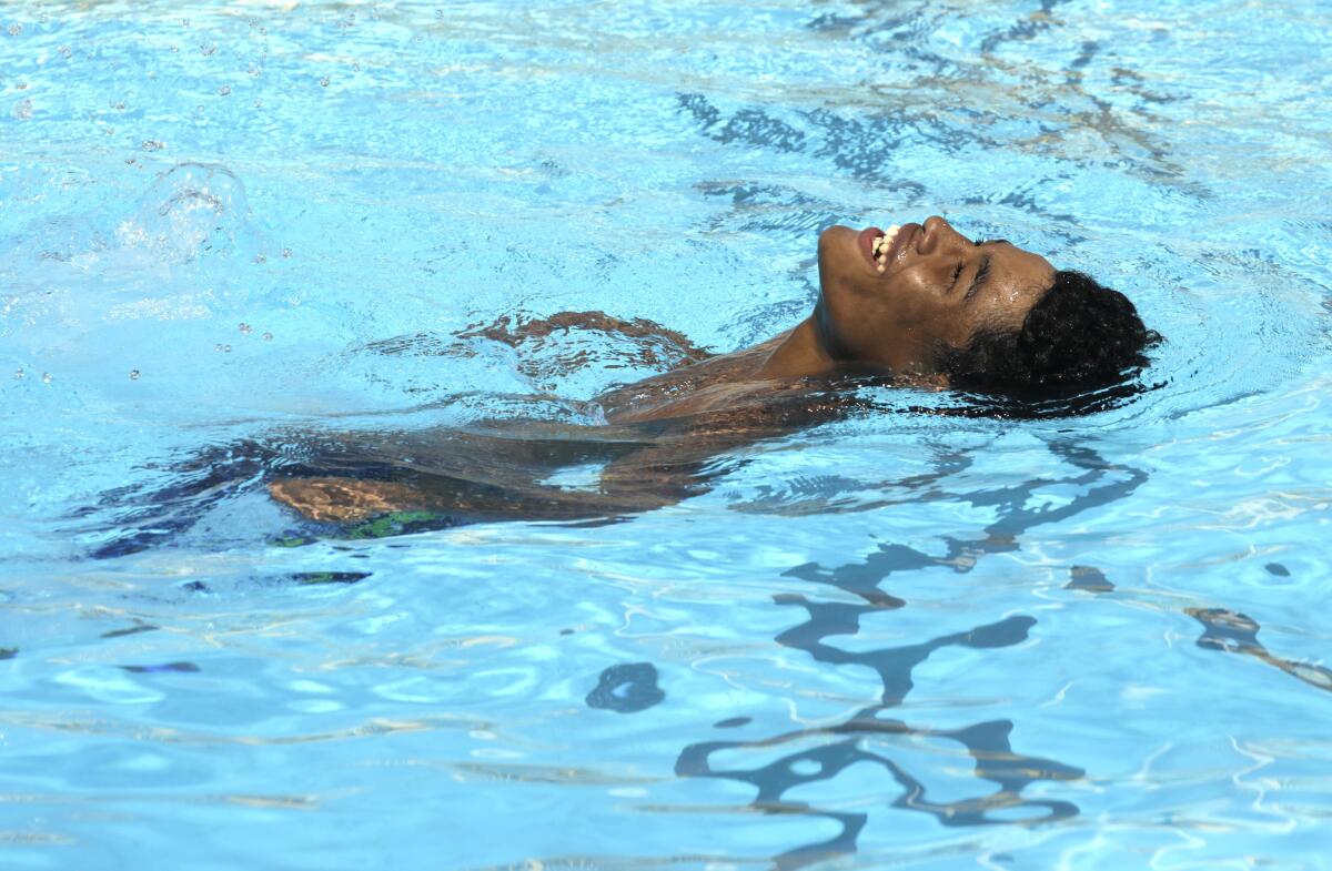 A young man floats in a pool, smiling