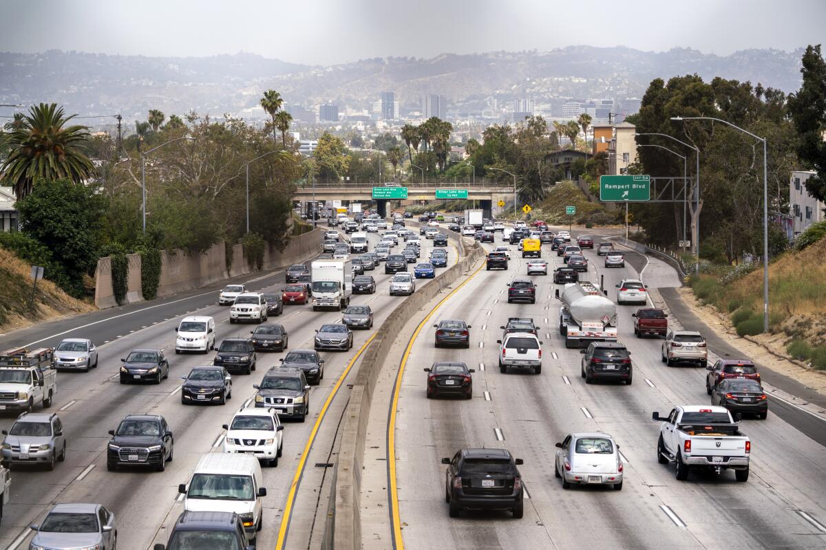 A view from above of an eight-lane highway with cars. Low hills are on the horizon.