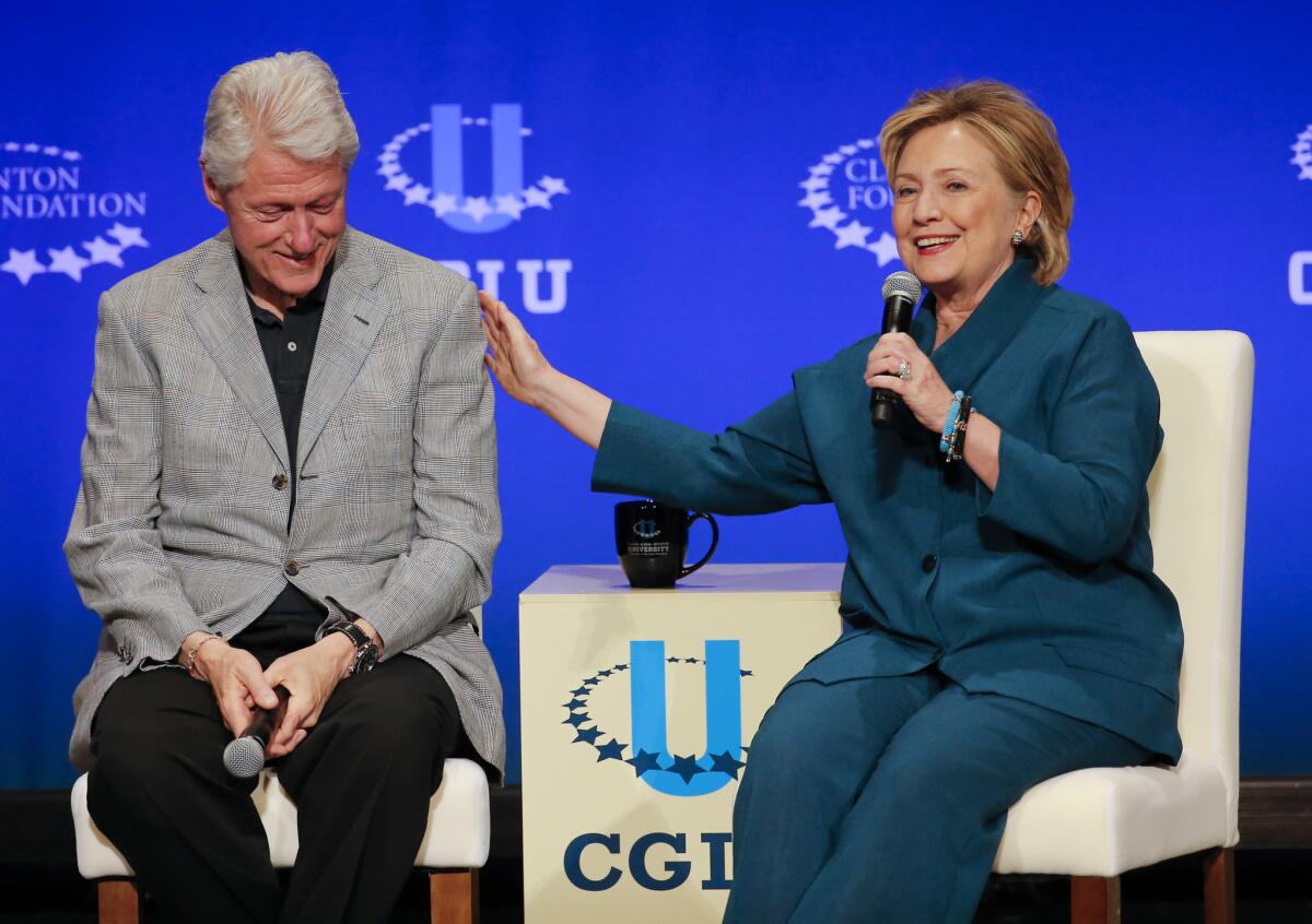 Former President Bill Clinton, left, listens as former Secretary of State Hillary Rodham Clinton speaks during a student conference for the Clinton Global Initiative University at Arizona State University in Tempe, Ariz.