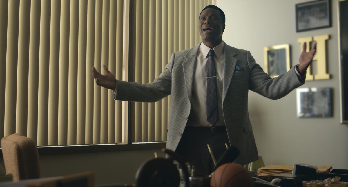 A man in a suit gesticulates in his office