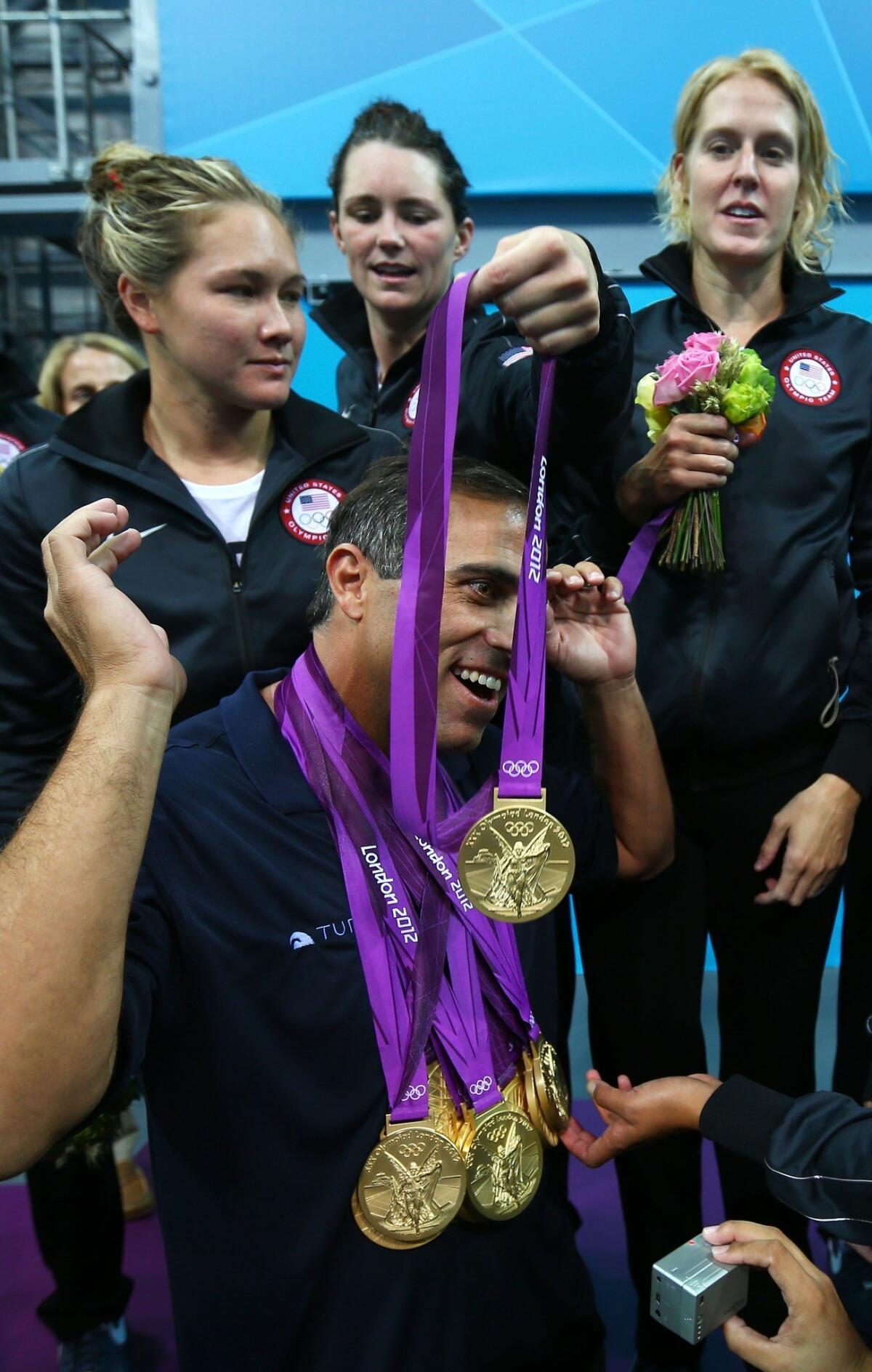 The U.S. women's water polo team honors coach Adam Krikorian by placing their gold medals around his neck at the 2012 London Olympic Games.
