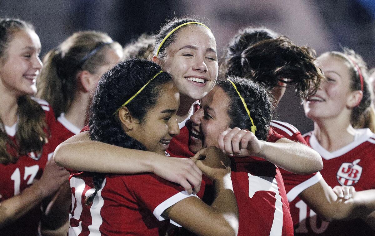 Burroughs' Olivia Aguilar pulls teammates Lauryn Bailey and Lily Gonzalez together for a celebratory embrace after learning the team is Pacific League champions after defeating rival Burbank in the final regular girl's soccer game of the season at Burroughs High School on Thursday, January 31, 2019. Burroughs won the game 5-1.