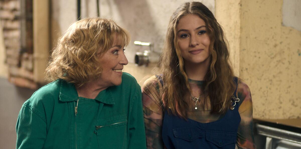 An older blond woman grinning at a teenage girl.