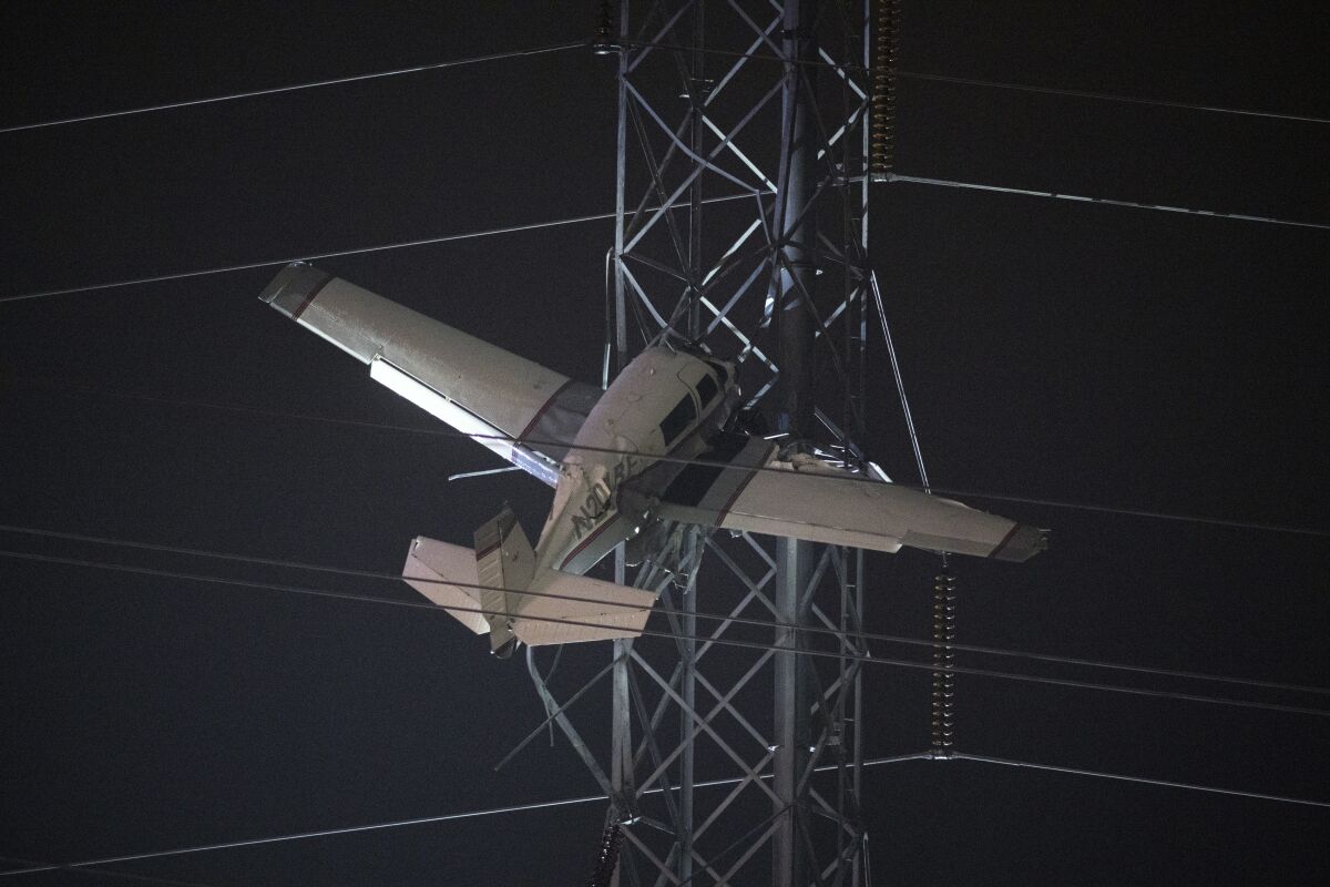 A small plane rests on live power lines after crashing, Sunday, Nov. 27, 2022, in Montgomery Village, a northern suburb of Gaithersburg, Md. (AP Photo/Tom Brenner)
