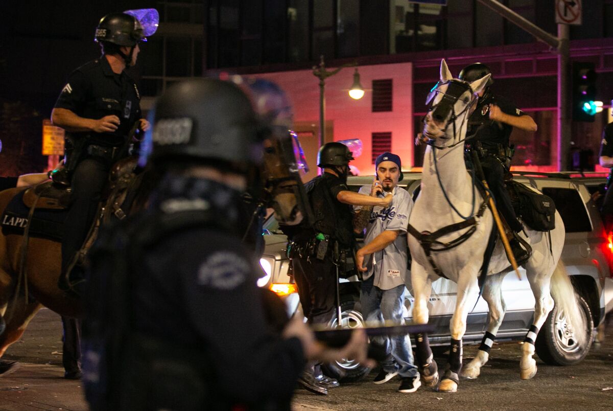 LAPD officers on horseback move in to disperse the crowds in downtown Los Angeles after the Dodgers win the World Series.