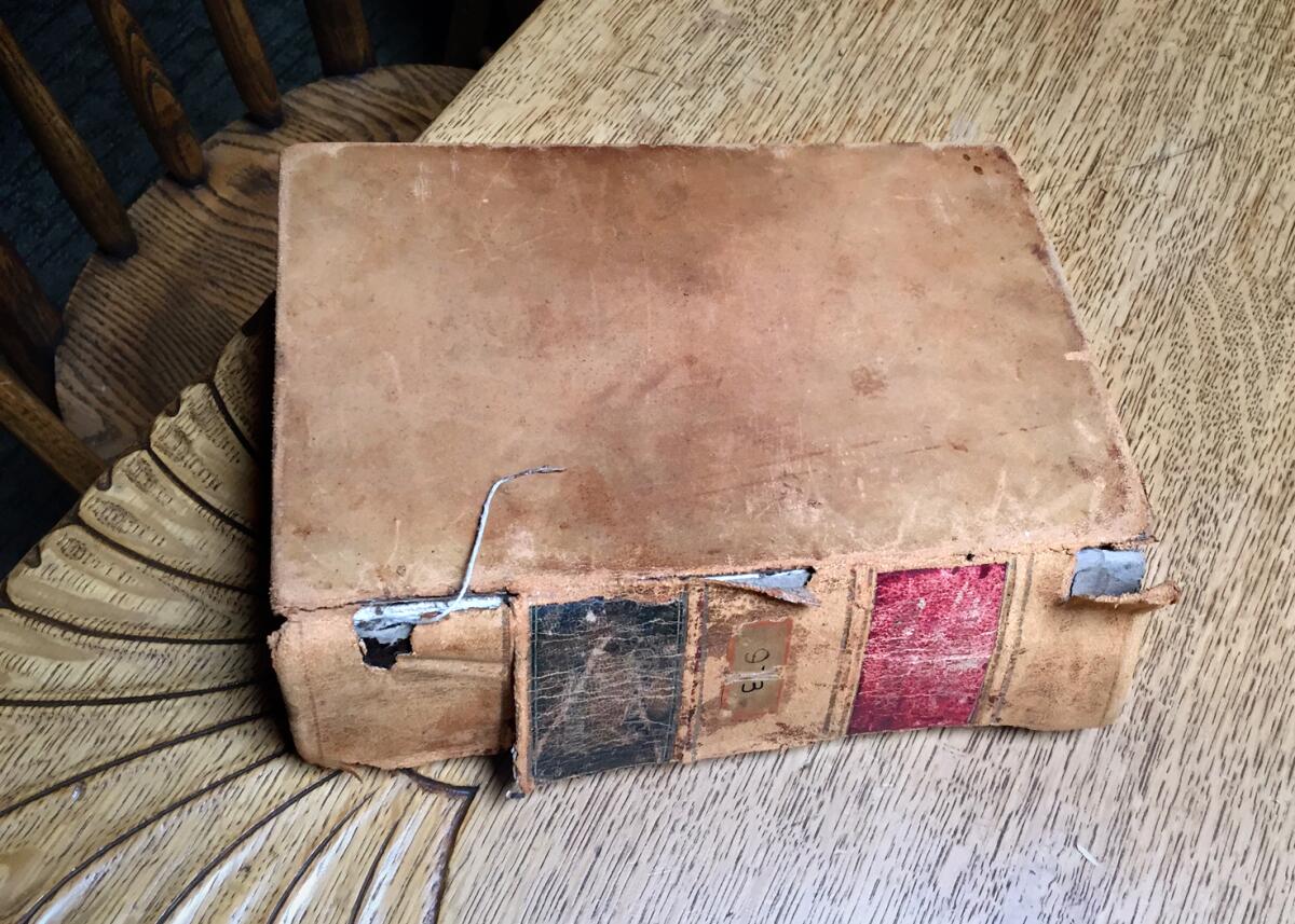 A well-worn leather-bound book lays closed on a table.