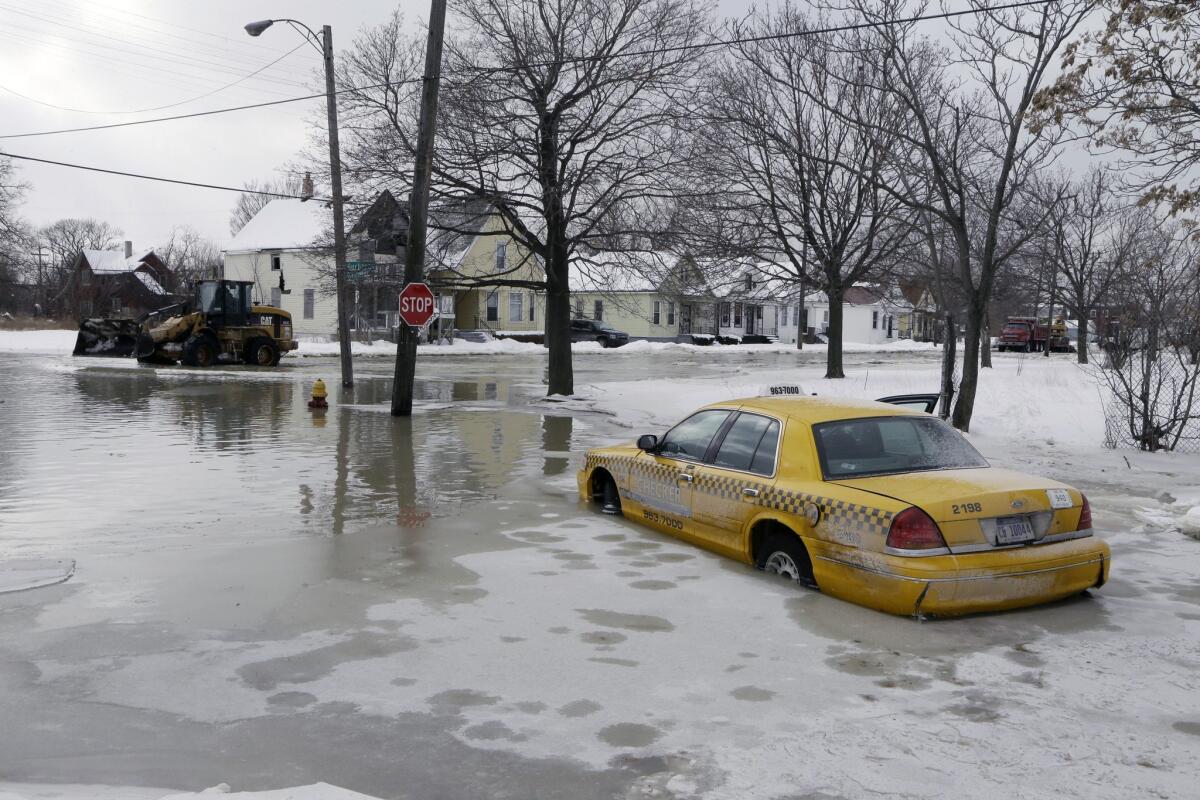 FILE - In this Feb. 11, 2014 file photo, a taxi cab is surrounded by water on a flooded street after a water main break flooded several blocks in Detroit. The relentless cycle of snow and bitter cold this winter is testing the skeletons of steel and cement on which communities are built. Pipes are bursting in towns that are not used to such things, and roads are turning into moonscapes of gaping potholes big enough to snap axles of passing vehicles. (AP Photo/Carlos Osorio, File) ** Usable by LA and DC Only **