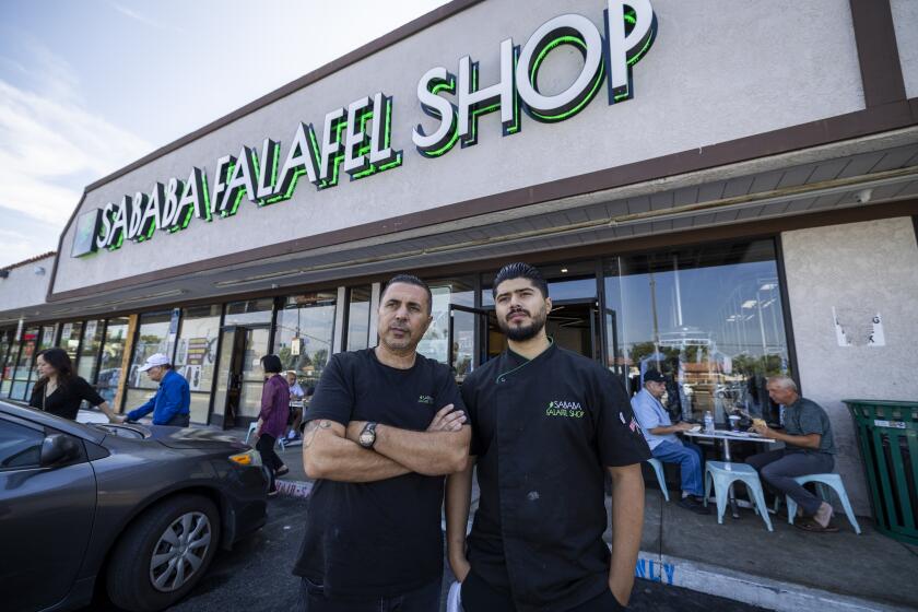 Garden Grove, CA - October 09: Sal Othman, left, owner, and his son Mohammad Othman, manager, of Sababa Falafel Shop in Garden Grove, who are Palestinians, stand in front of their business after speaking about their concerns to the rising conflict in the Gaza-Israel War Monday, Oct. 9, 2023. (Allen J. Schaben / Los Angeles Times)