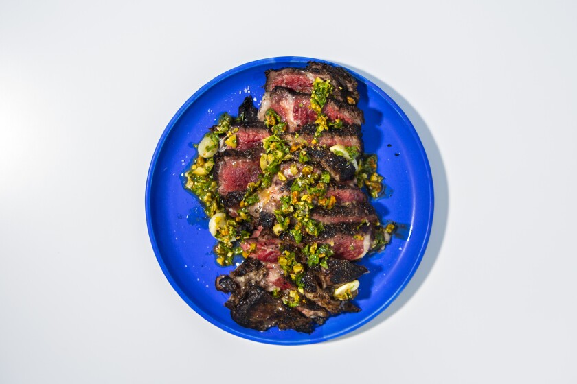 Aged ribeye steak with pistachio gremolata on a blue plate