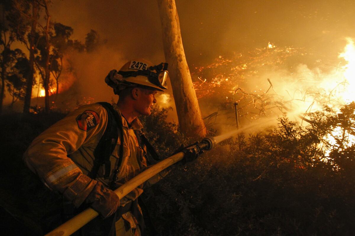 A Cal Fire firefighter hoses a hillside during the Lilac Fire in 2017. 