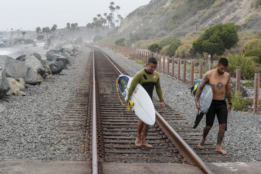 Surfers cross the railroad tracks near San Clemente's North Beach.