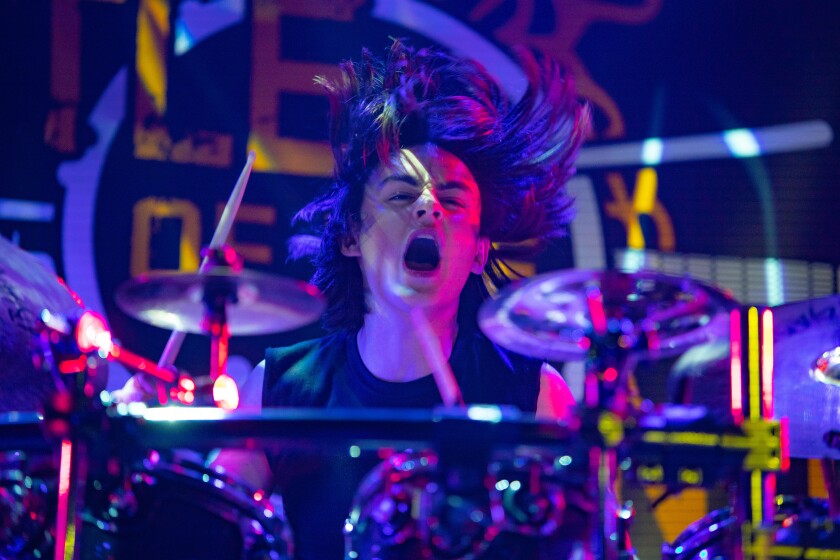 A young man with long hair plays the drums in the movie “Metal Lords.”