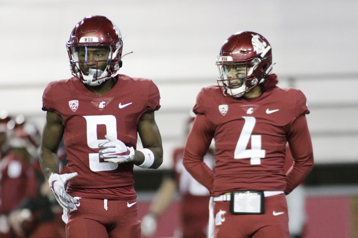 Washington State wide receiver Renard Bell and quarterback Jayden de Laura stand on the field.