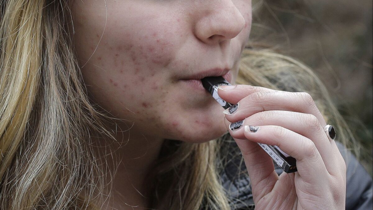 A teenager uses a vaping device near her school in Cambridge, Mass. A California bill to stop teen use of electronic cigarettes was shelved earlier this year.