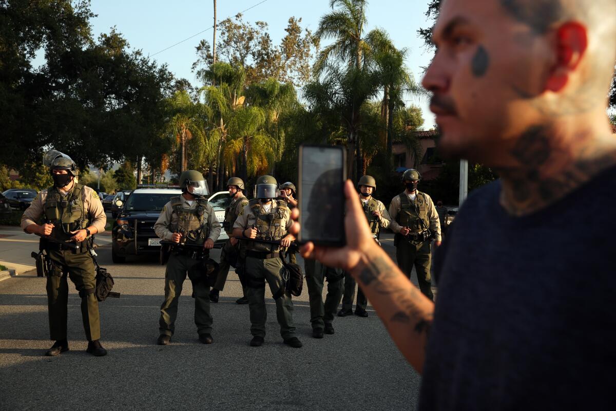 Person documents line of sheriff's deputies during a picket organized by the Coalition for Community Control Over the Police