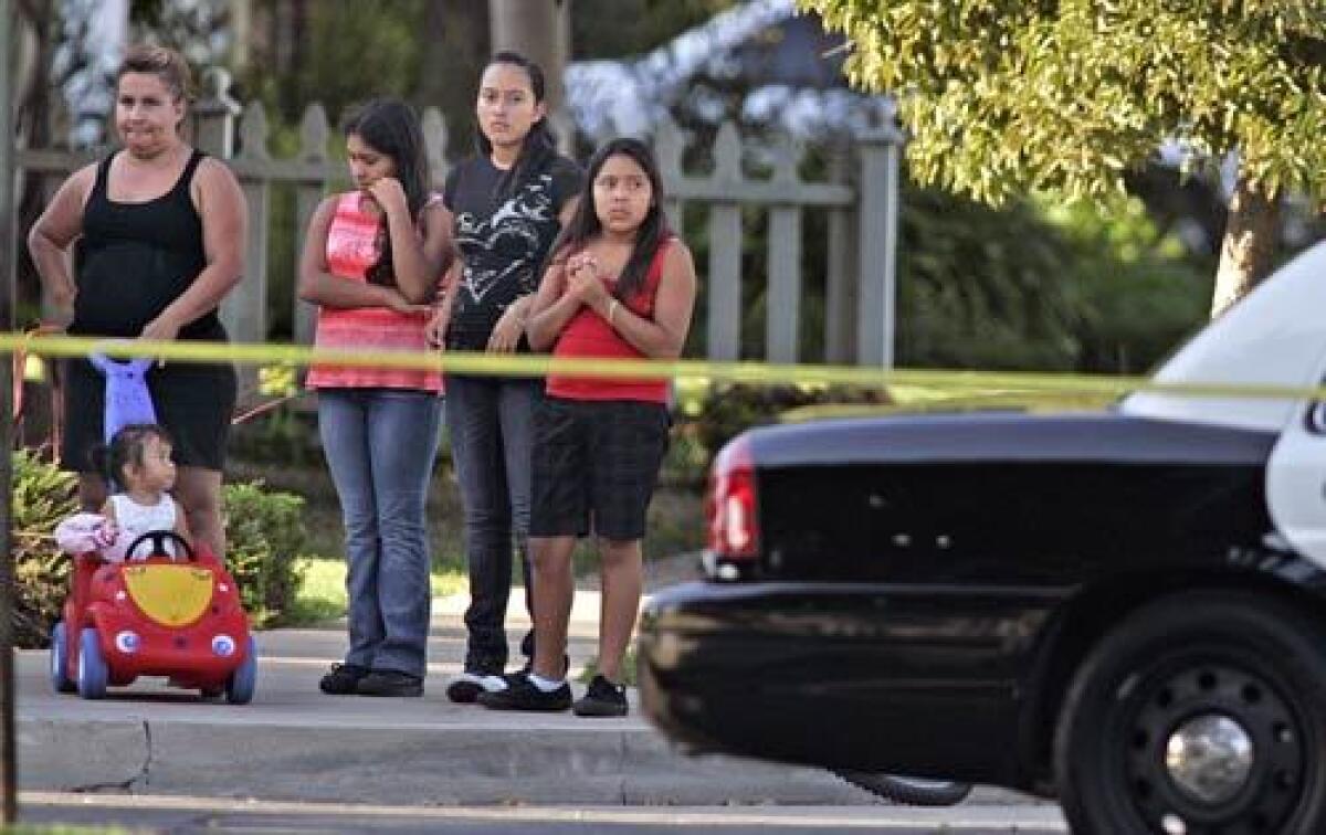Residents of Lowell Lane in Santa Ana gather near a where a woman was found dead in a home.