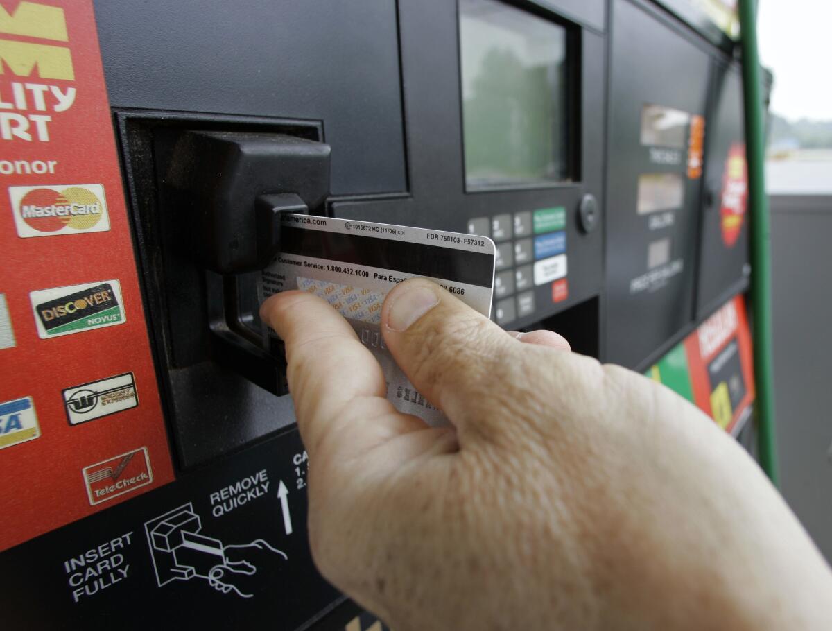 A customer swipes a credit card at a gas station pump. 