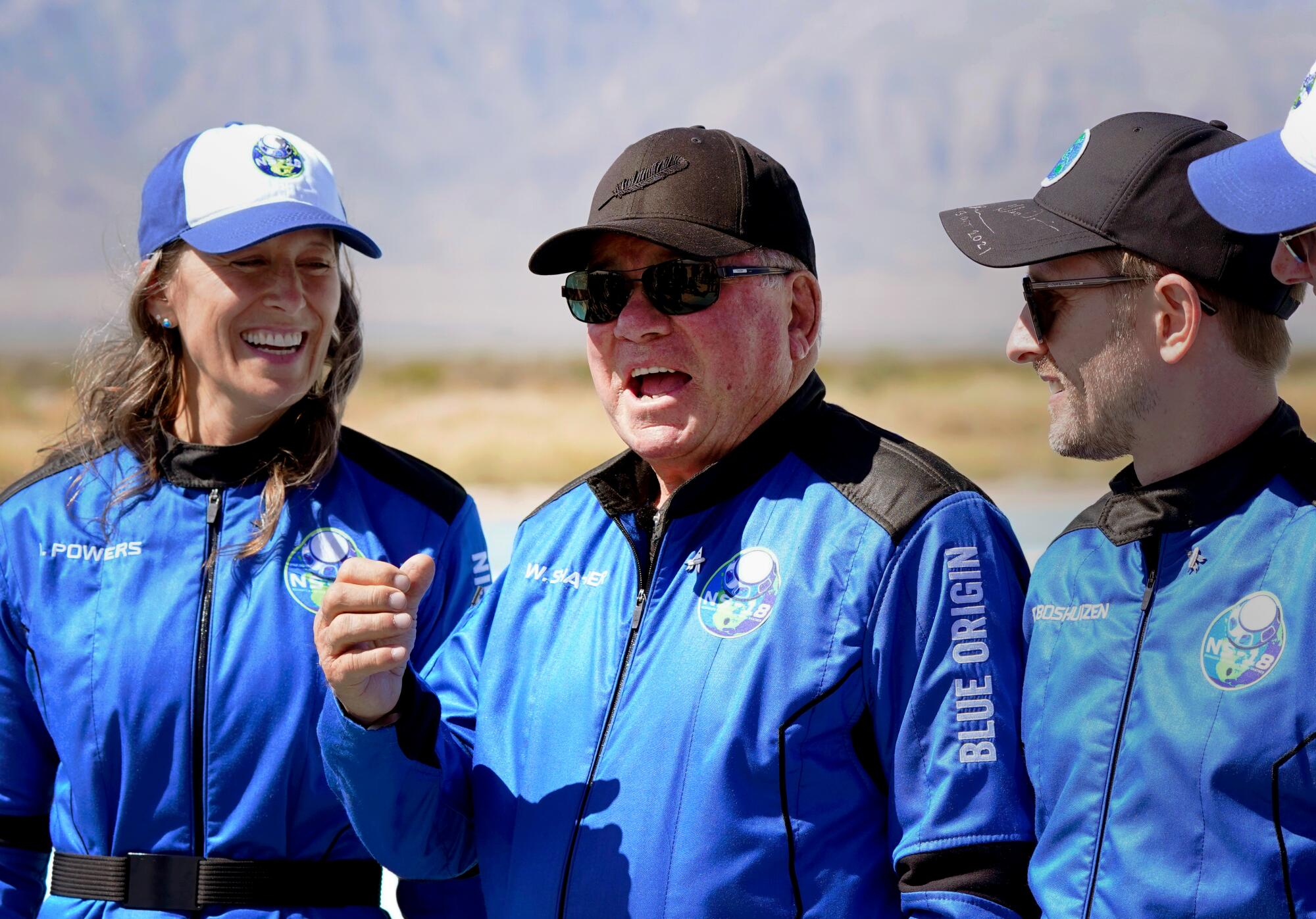 Three people in blue flight suits and baseball caps.