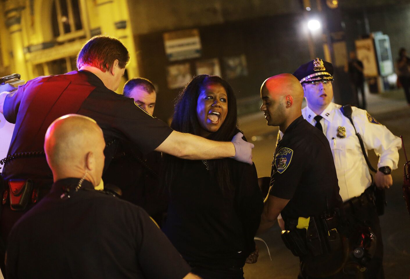 A woman is loaded into the back of a van after being arrested for violating a 10 p.m. curfew Saturday in Baltimore.