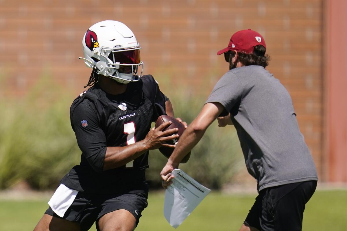 Arizona Cardinals quarterback Kyler Murray (1) eludes quarterbacks coach Cam Turner as Murray takes part in drills at the NFL football team's practice facility on Tuesday, June 14, 2022, in Tempe, Ariz. (AP Photo/Ross D. Franklin)