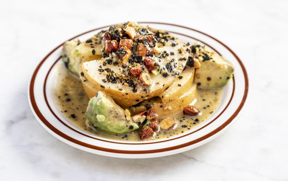 A plate holds a salad of dressed avocado and Asian pear. 