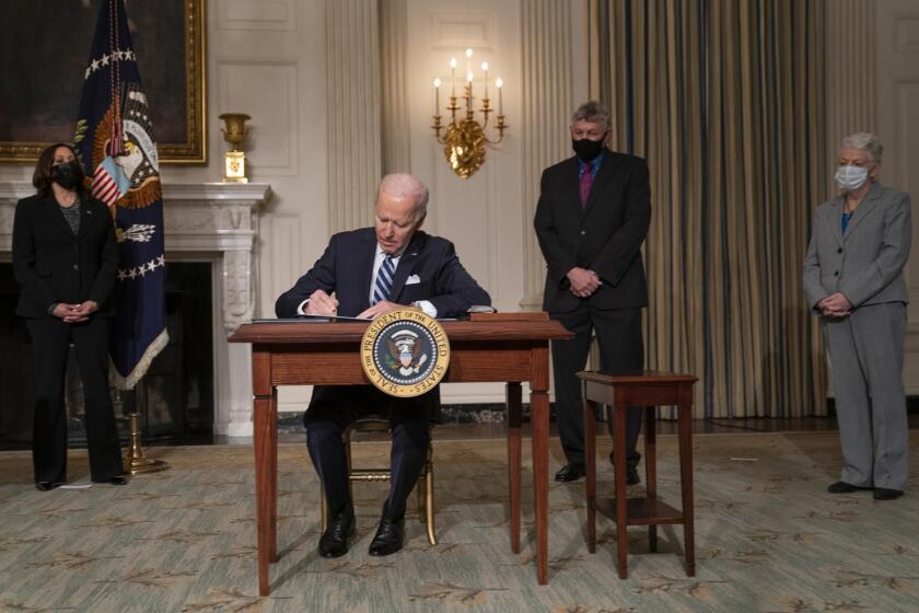 President Joe Biden signs a series of executive orders on climate change, in the State Dining Room of the White House, Wednesday, Jan. 27, 2021, in Washington. From left, Vice President Kamala Harris, Biden, White House science adviser Dr. Eric Lander, and National Climate Adviser Gina McCarthy. (AP Photo/Evan Vucci)