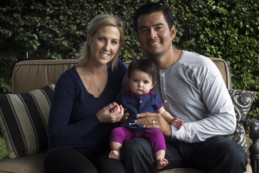 Recently acquired Angels pitcher Cesar Ramos, right, sits at home with his wife, Melanie, and their four-month-old daughter, Addison, on Nov. 19. Melanie was diagnosed with Hodgkin's lymphoma more than two years ago and underwent nine months of chemotherapy.