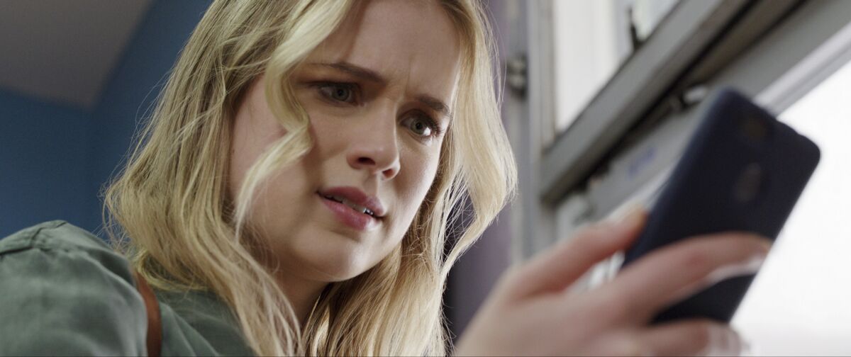 Elizabeth Lail checks her phone in the movie "Countdown."