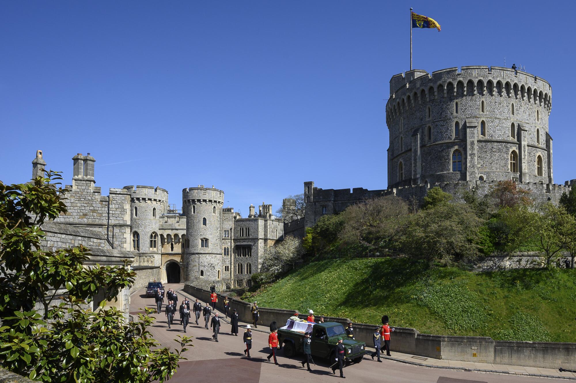 Royal family members walk behind Prince Philip's coffin as it is driven  on a modified Land Rover by the Round Tower.